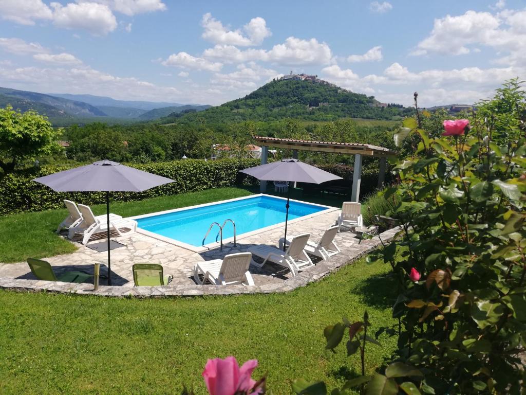 una piscina con sillas y sombrillas en un patio en Guest House Valentino en Motovun