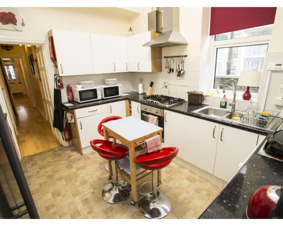 a kitchen with white cabinets and red bar stools at Parasol Weston Guest House in Weston-super-Mare