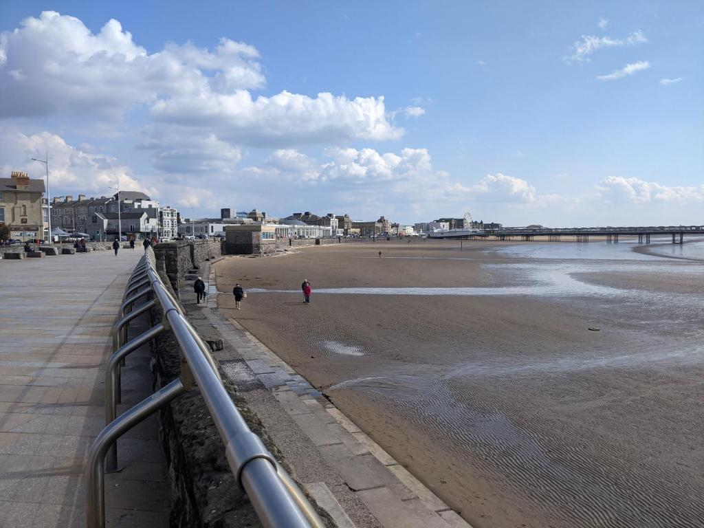 a beach with people walking on the sand and a pier at Parasol Weston Guest House in Weston-super-Mare