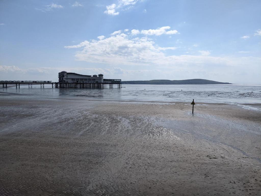 a person standing on the beach near a pier at Parasol Weston Guest House in Weston-super-Mare