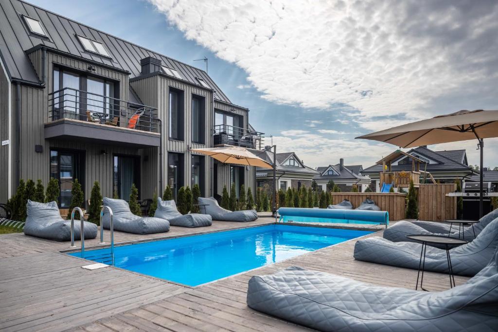 a pool with chairs and umbrellas next to a building at Green Shine Apartment, By Cohost in Palanga