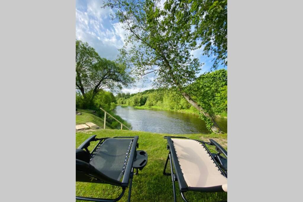 a boat parked on the grass next to a river at Cabin by the river Dubysa! in Ariogala