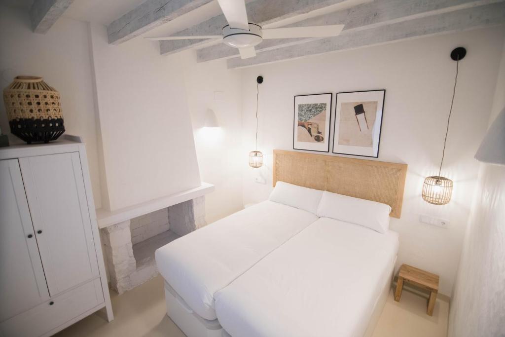 a white bedroom with a white bed and two pictures at Quinta la Sal in Jávea