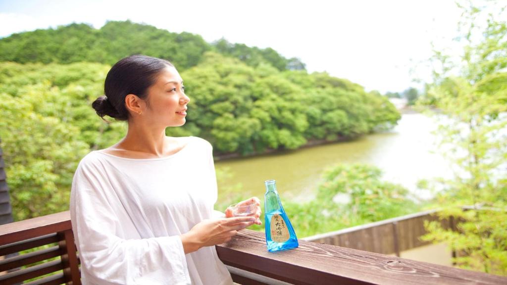 a woman standing on a bench holding a drink at Hotel Allamanda大人の隠れ家リゾート in Nara