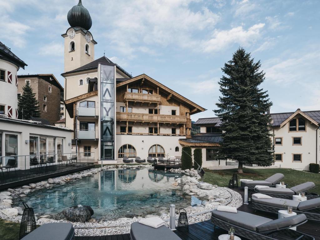 a hotel with a swimming pool in front of a building at VAYA Post Saalbach in Saalbach-Hinterglemm