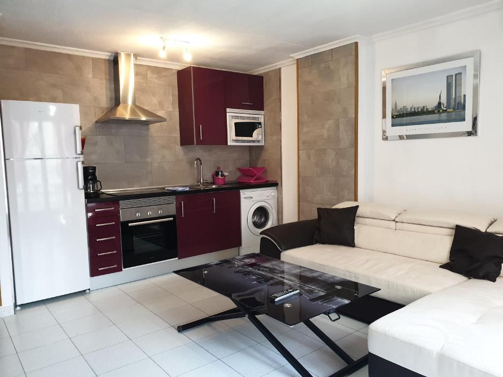 a living room with a white couch and a kitchen at Penthouse Residencial Virginia in Torrevieja