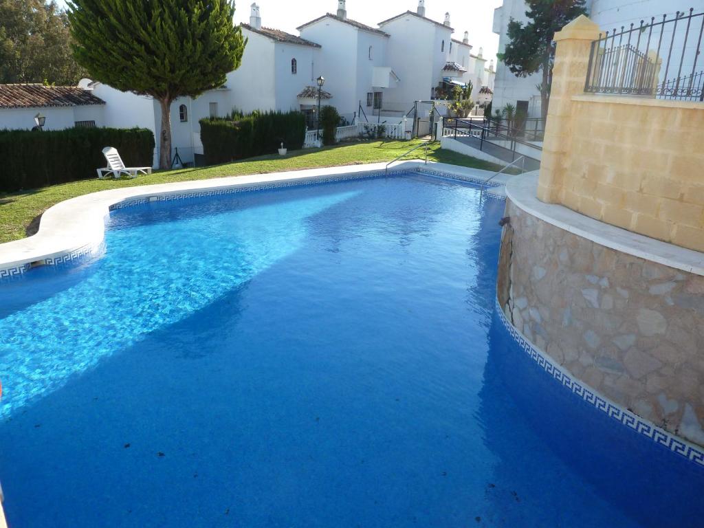 a swimming pool with blue water in a yard at Playa Golf Apartamentos con Piscina in Benalmádena