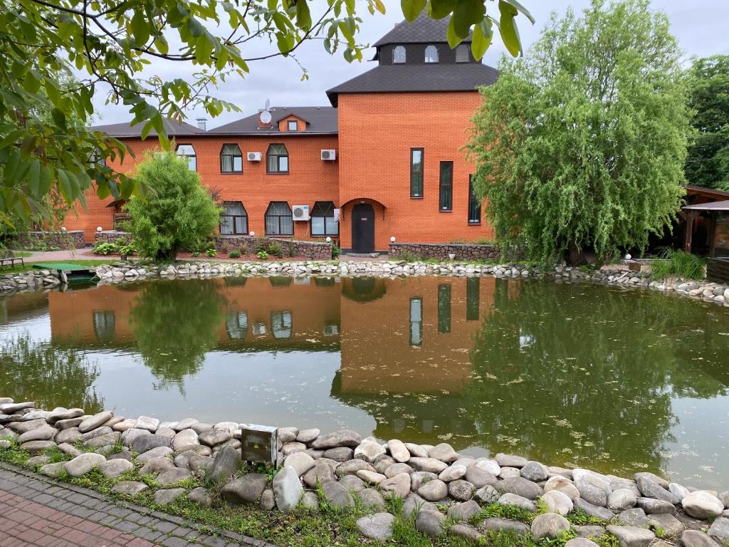 a building with a pond in front of a building at Гостинний маєток in Myla