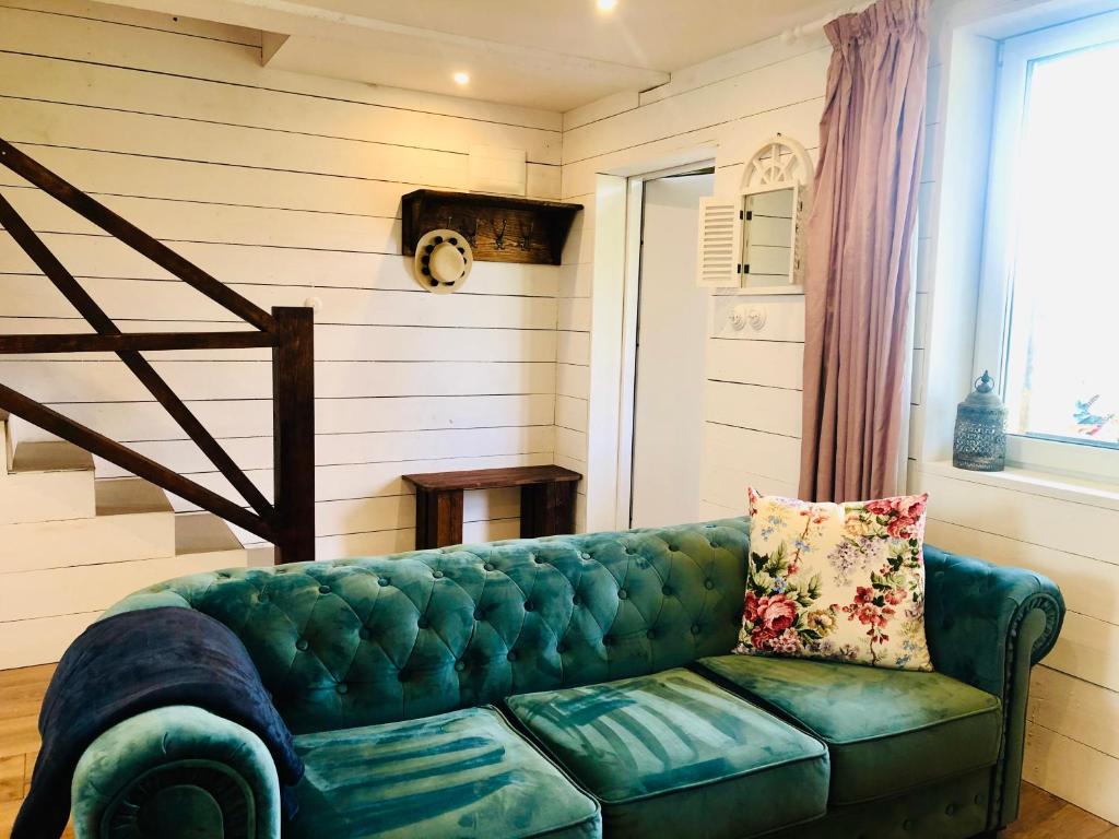 a green couch in a living room with a window at Goose Home and Garden in Łeba