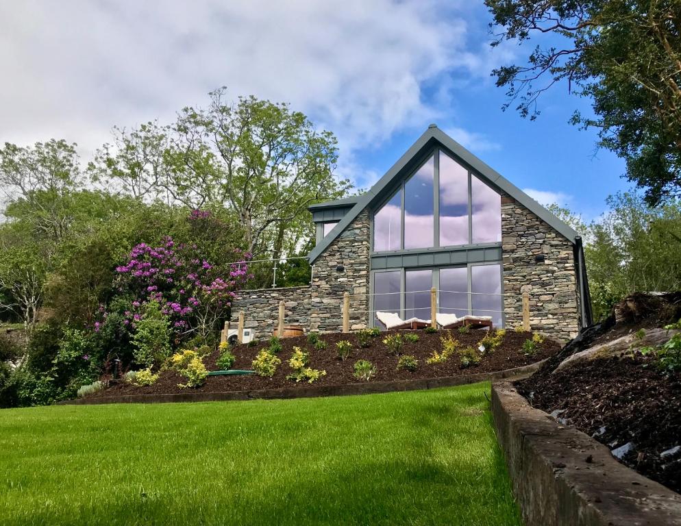 una casa con un patio verde y una casa de piedra en Patch House Glengarriff, en Glengarriff