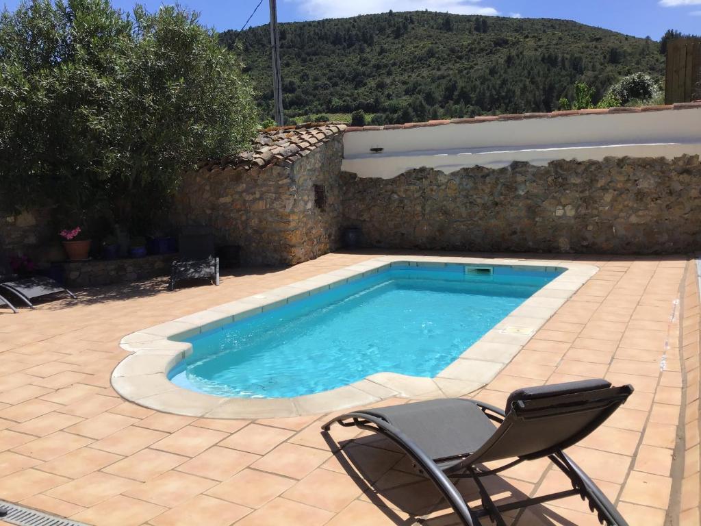 a swimming pool with a chair next to a wall at Maison de la Fontaine in Embres-et-Castelmaure
