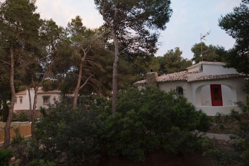 a white house with a red window and trees at Quinta la Sal in Jávea