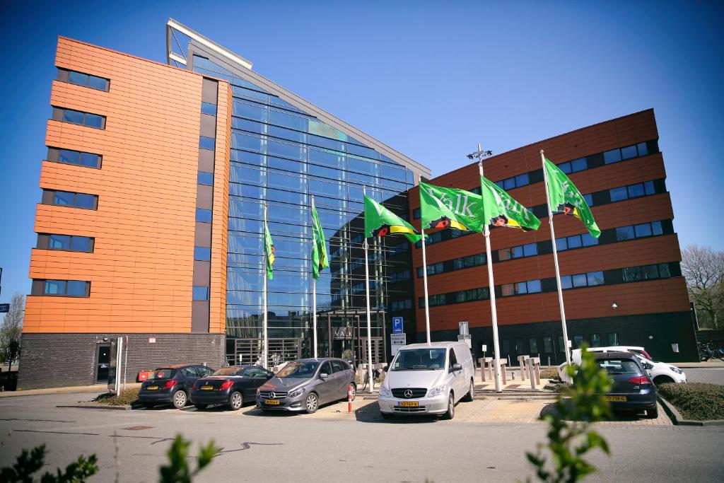 een gebouw met auto's geparkeerd op een parkeerplaats bij Van der Valk Hotel Rotterdam - Blijdorp in Rotterdam