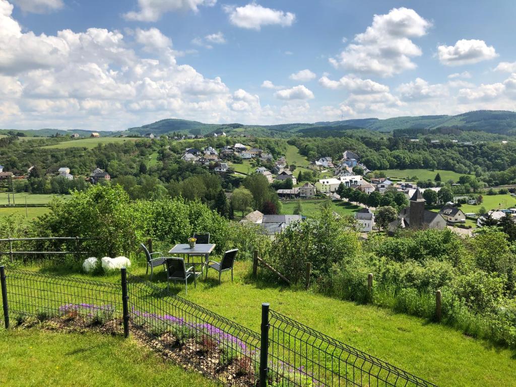 Blick auf ein Dorf von einem Hügel mit einem Tisch und Stühlen in der Unterkunft Ardenne View in Wilwerwiltz