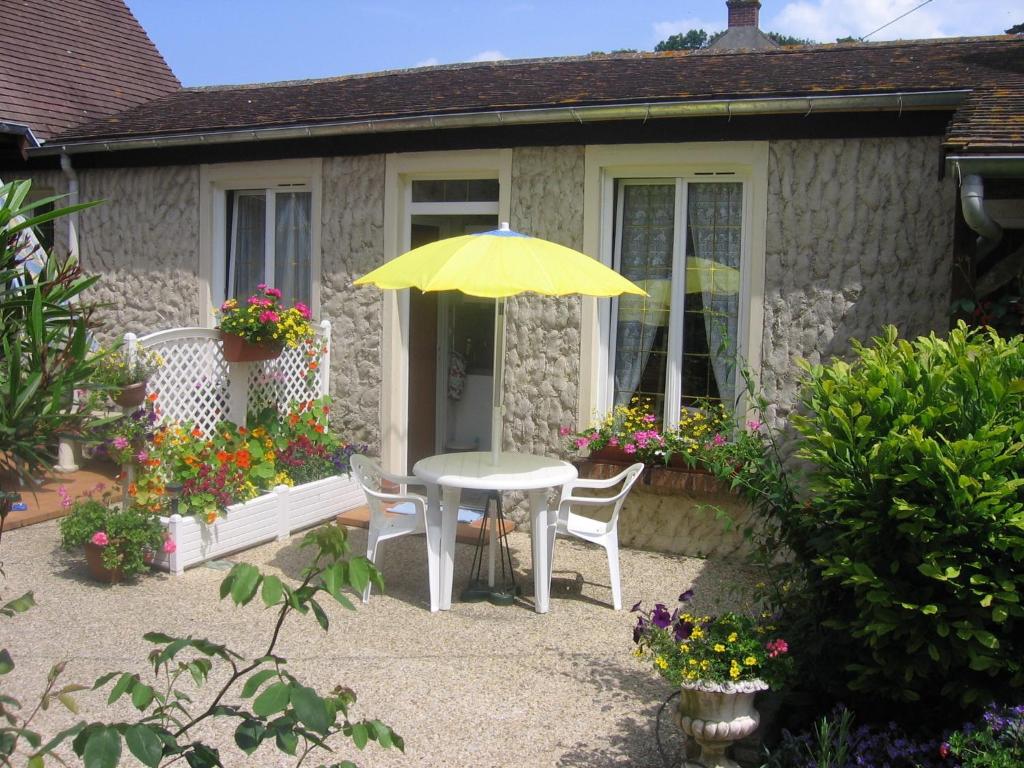 a table and chairs with an umbrella in front of a house at Au Bon Gite - Studio in Arromanches-les-Bains