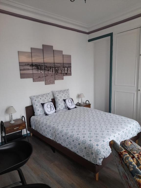 - une chambre avec un grand lit et une chaise dans l'établissement Le DINGSON, à Arromanches-les-Bains