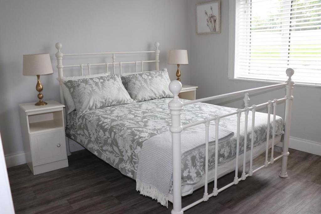 a white bed in a white bedroom with two night stands at WILLOW COUNTRY COTTAGE in Killarney