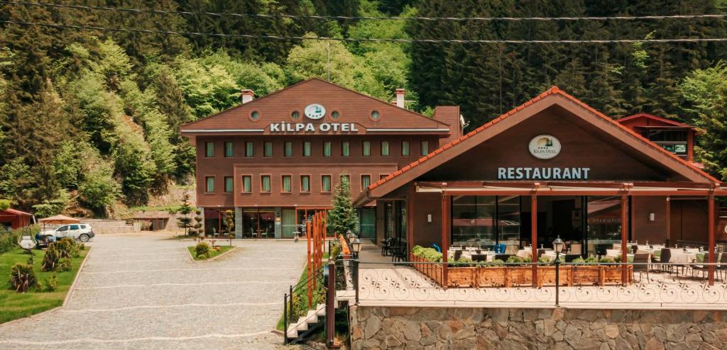 un grand bâtiment avec un restaurant dans un parking dans l'établissement Kilpa Hotel, à Uzungöl