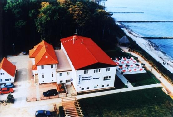 un gran edificio con techo rojo junto al océano en Hotel Nienhäger Strand, en Ostseebad Nienhagen