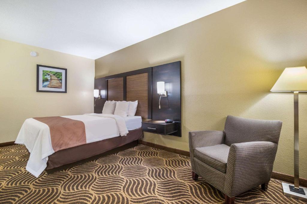 a hotel room with a bed and a chair at Quality Inn & Suites Florence - Cincinnati South in Florence