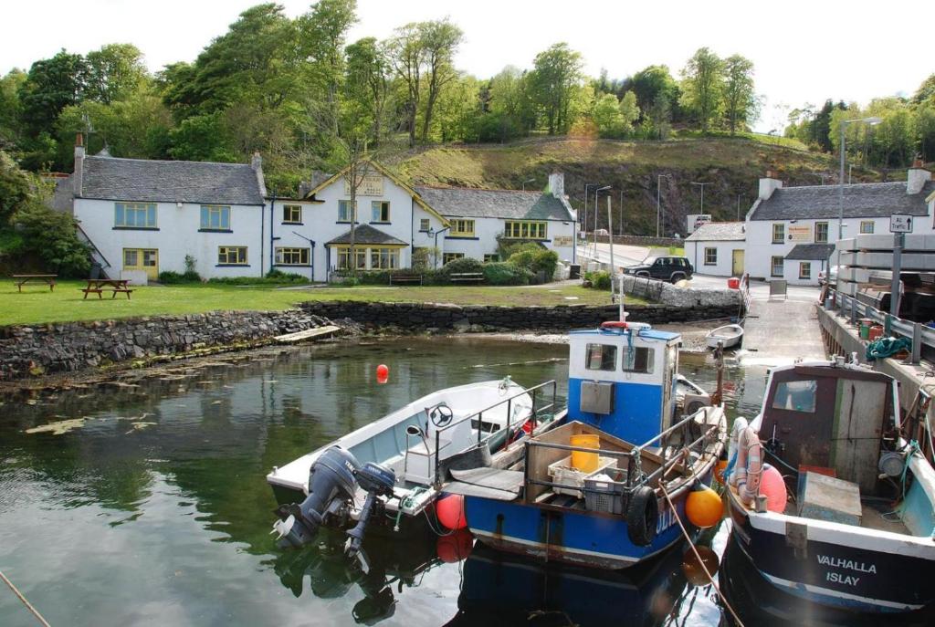 two boats docked in a marina in front of houses at Port Askaig Hotel in Port Askaig