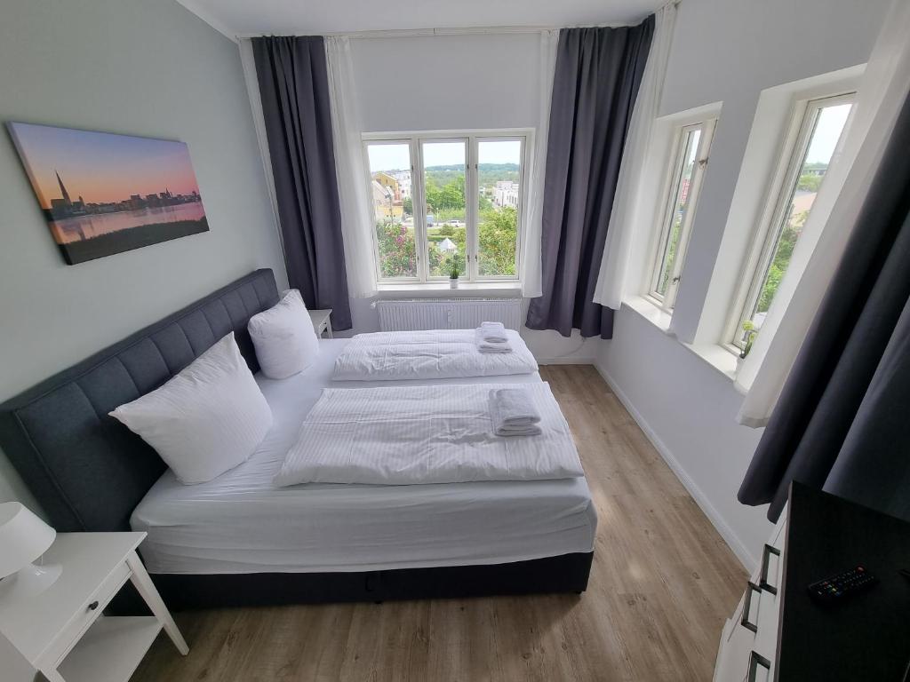 a small bedroom with a bed and two windows at Nikolai Appartements in Rostock