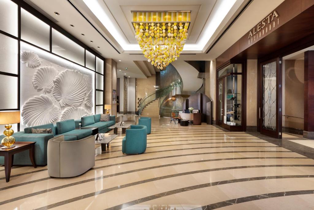 un vestíbulo de un hotel con sillas azules y una lámpara de araña en Titanic Business Kartal en Estambul