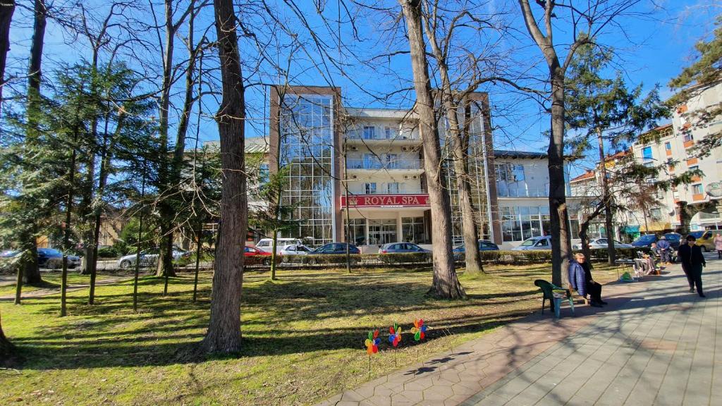 a person sitting on a park bench in front of a building at Hotel Royal Spa in Banja Koviljača