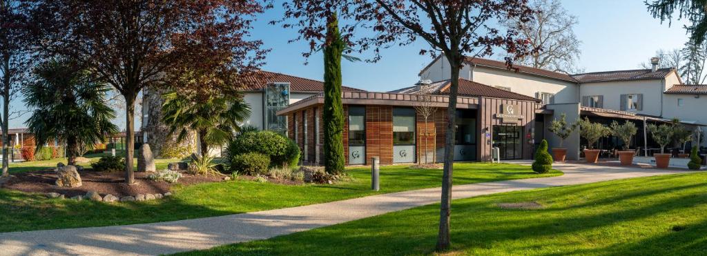 a house with a green lawn in front of it at Domaine la Charpinière, The Originals Collection in Saint-Galmier