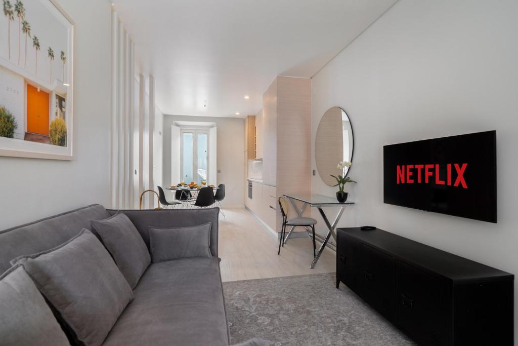 a living room with a gray couch and a kitchen at Beato HUB Residences | Perfect for Digital Nomads & Families in Lisbon