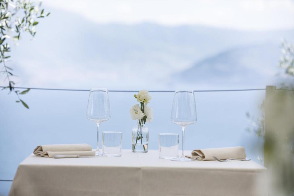 a table with glasses and flowers in a vase on it at Hotel Miranda in Riva di Solto