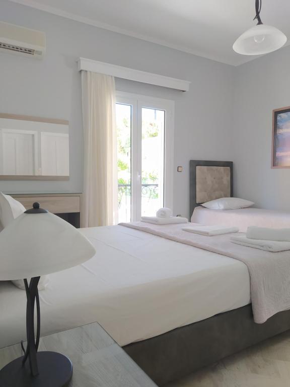a white bedroom with two beds and a lamp at Christina's House in Parga