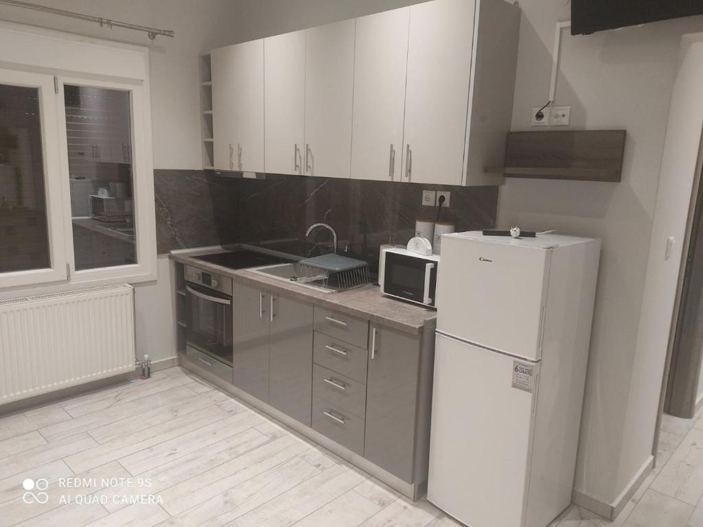 a kitchen with white cabinets and a white refrigerator at City Room in Volos