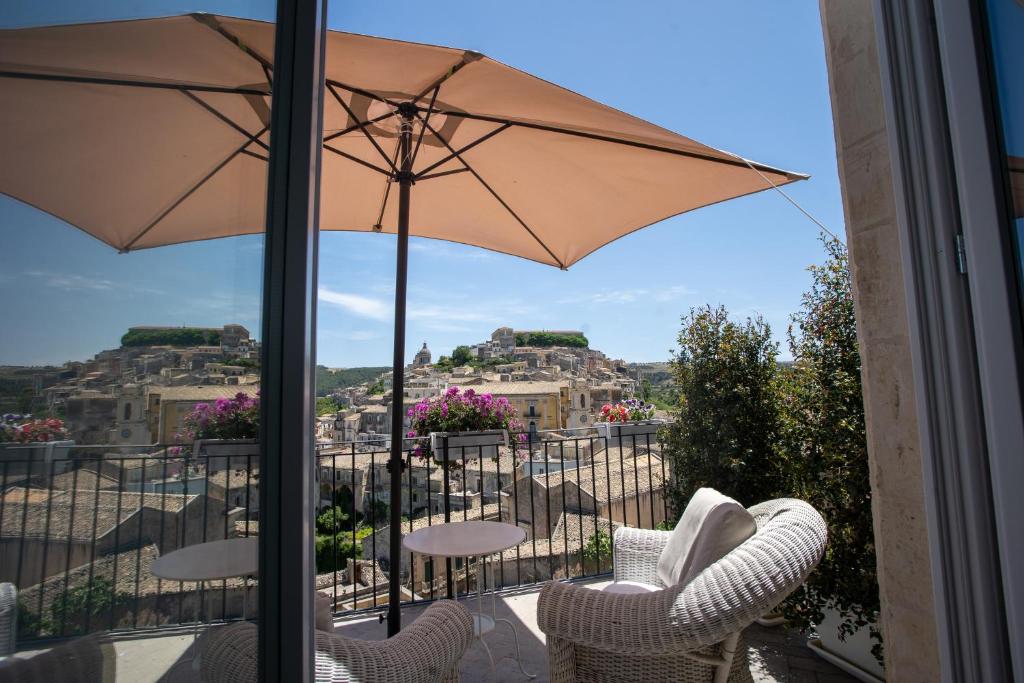 a patio with an umbrella and chairs on a balcony at Bed and Breakfast Terra del Sole Ibla in Ragusa