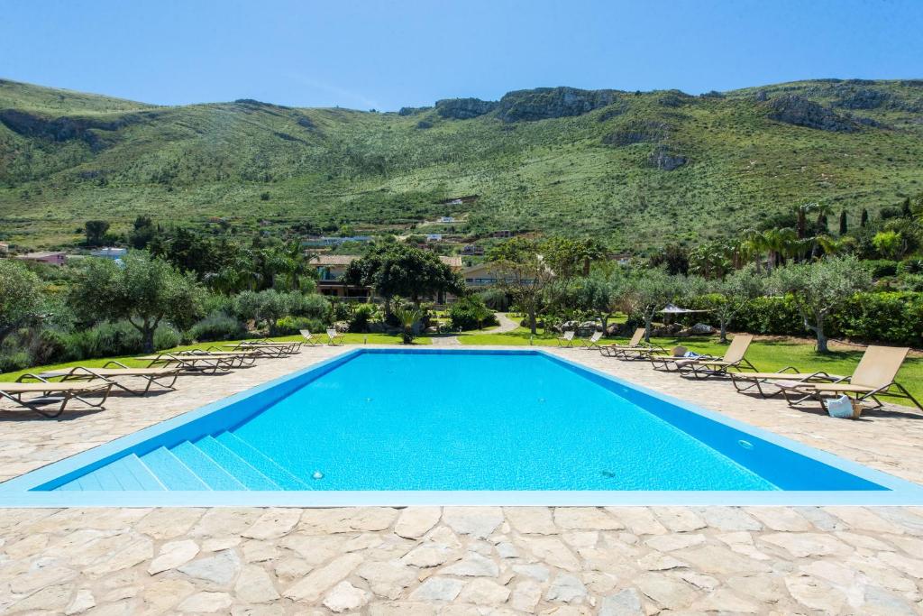 a swimming pool with chairs and mountains in the background at Ulivo Blu Holiday Homes in Castellammare del Golfo