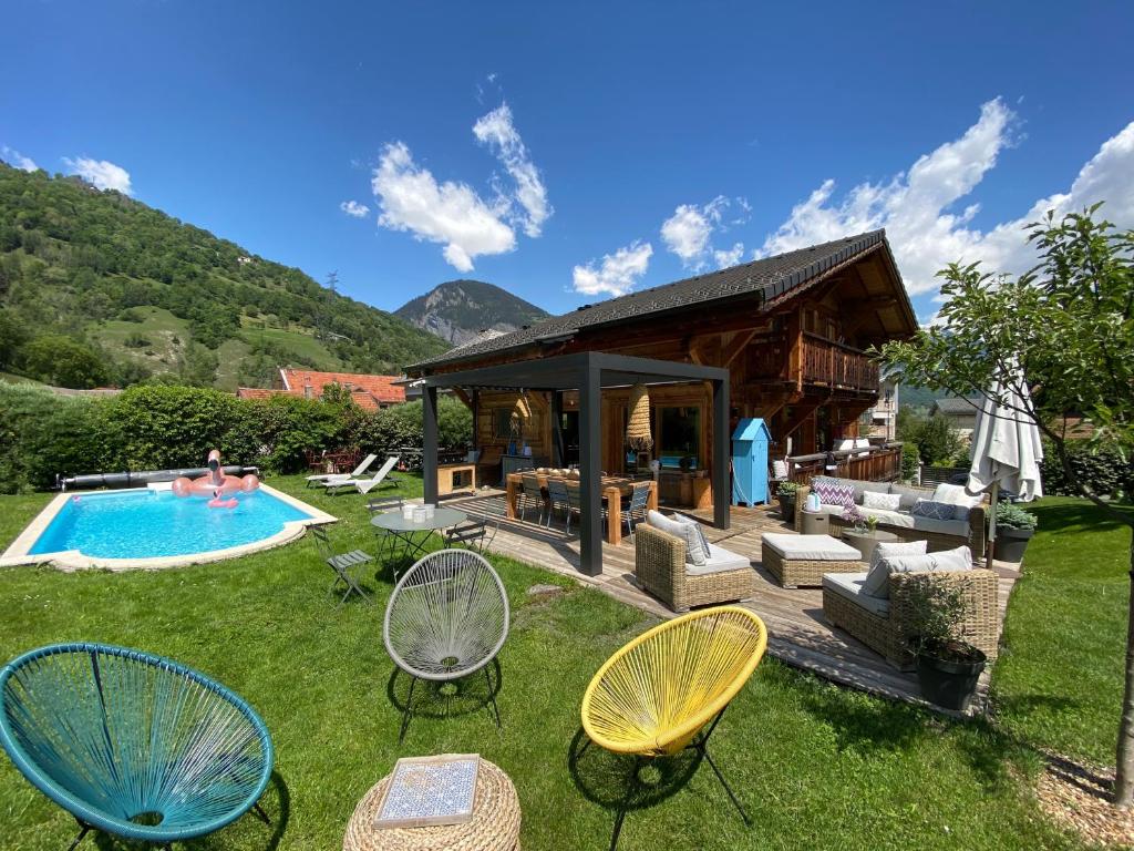 a backyard with a pool and chairs and a house at Grand chalet à la montagne in Bourg-Saint-Maurice