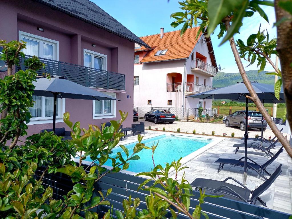 a swimming pool with chairs and umbrellas next to a building at Premier House by RD Group in Korenica