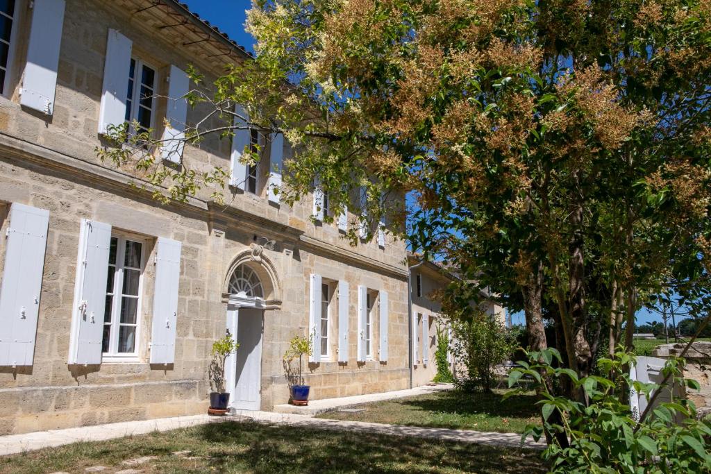 un viejo edificio con un árbol delante de él en La Girondine, en Saint-Philippe-dʼAiguille