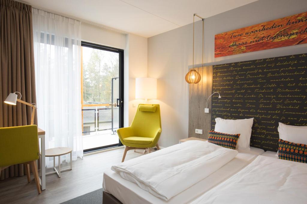 een hotelkamer met een bed en een gele stoel bij Landgoed ISVW in Leusden