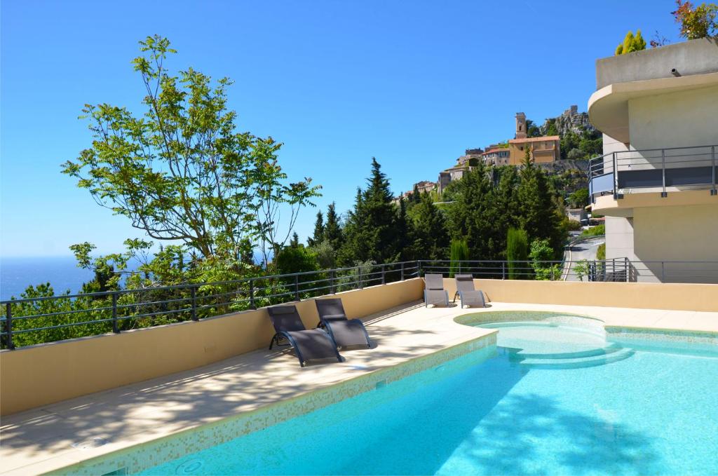 uma piscina com duas espreguiçadeiras ao lado de um edifício em La Perle d'Eze - Aparthotel em Èze