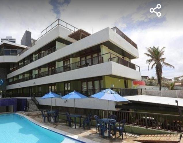 a large building with a pool and tables and umbrellas at Flat pé na areia Ponta Negra Natal RN 09 in Natal