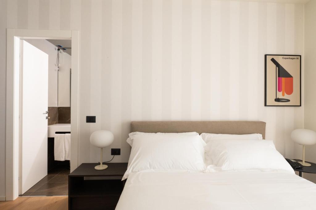 a bedroom with a white bed and a mirror at Hotel Punta Tipa in Trapani