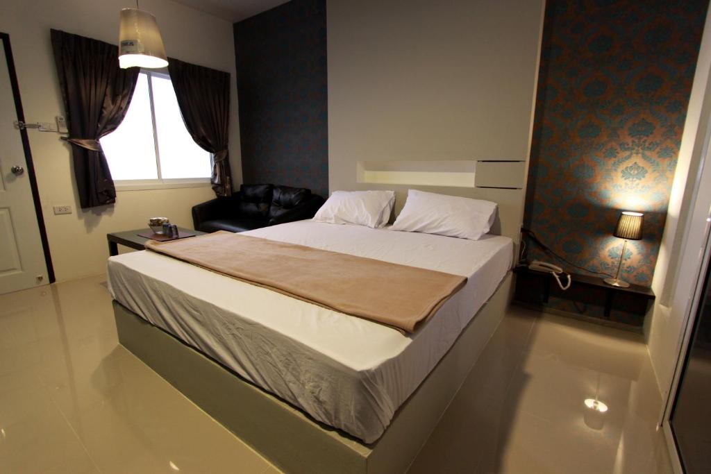 a bedroom with a bed and a chair and a window at Bearing26 Hotel in Bangna