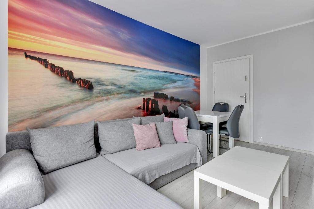 a living room with a couch and a painting of a pier at Grand Apartments - Silver Sands Sopot Apartment in Sopot