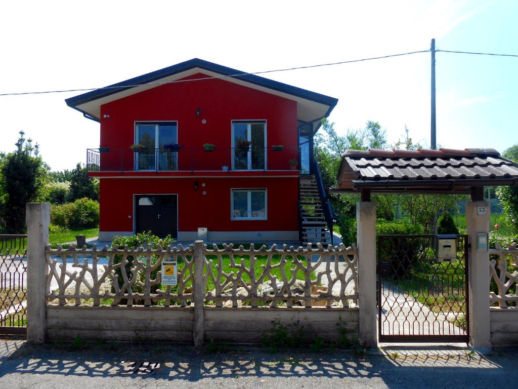 a red house behind a fence with a gate at VCE House in Tessera