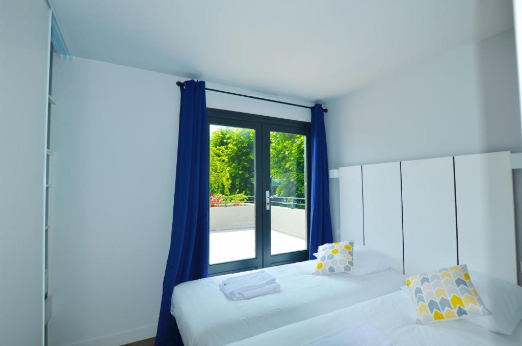 a bedroom with two beds and a large window at La Perle d'Eze - Aparthotel in Éze