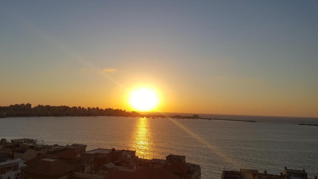 um pôr-do-sol sobre a água com casas e edifícios em Misr Hotel em Alexandria