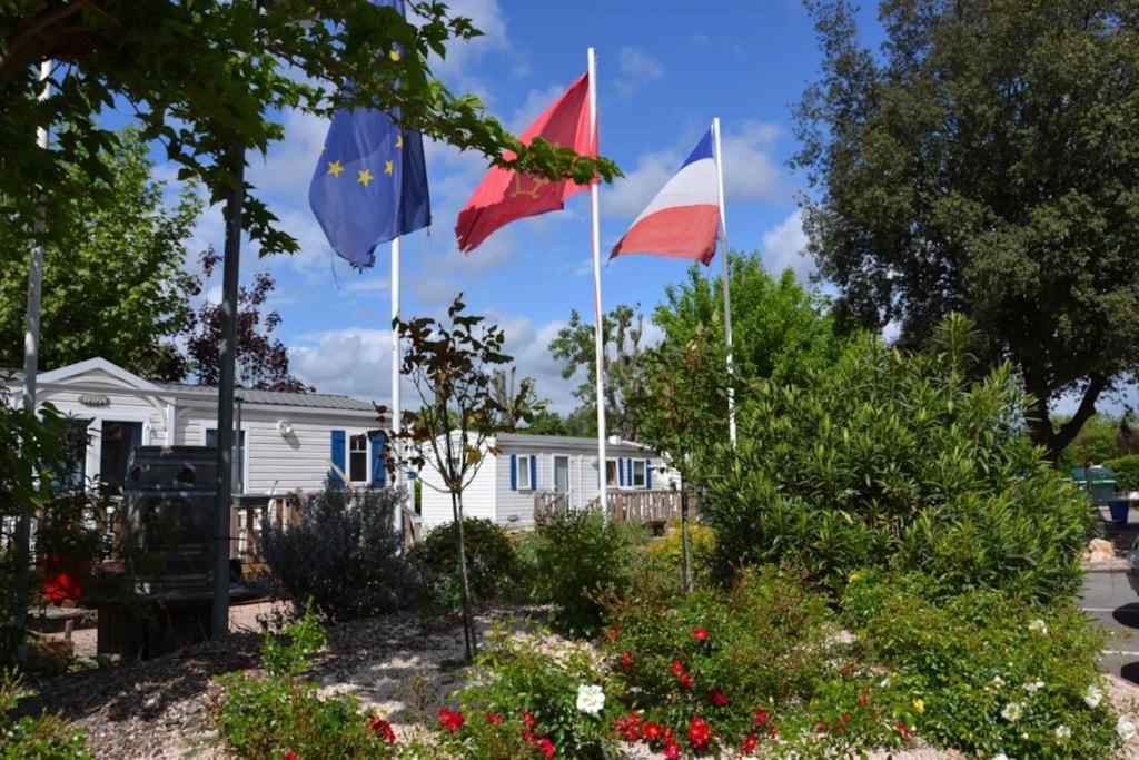 trois drapeaux battant devant une maison blanche dans l'établissement CAMPING LE RUPE, à Toulouse