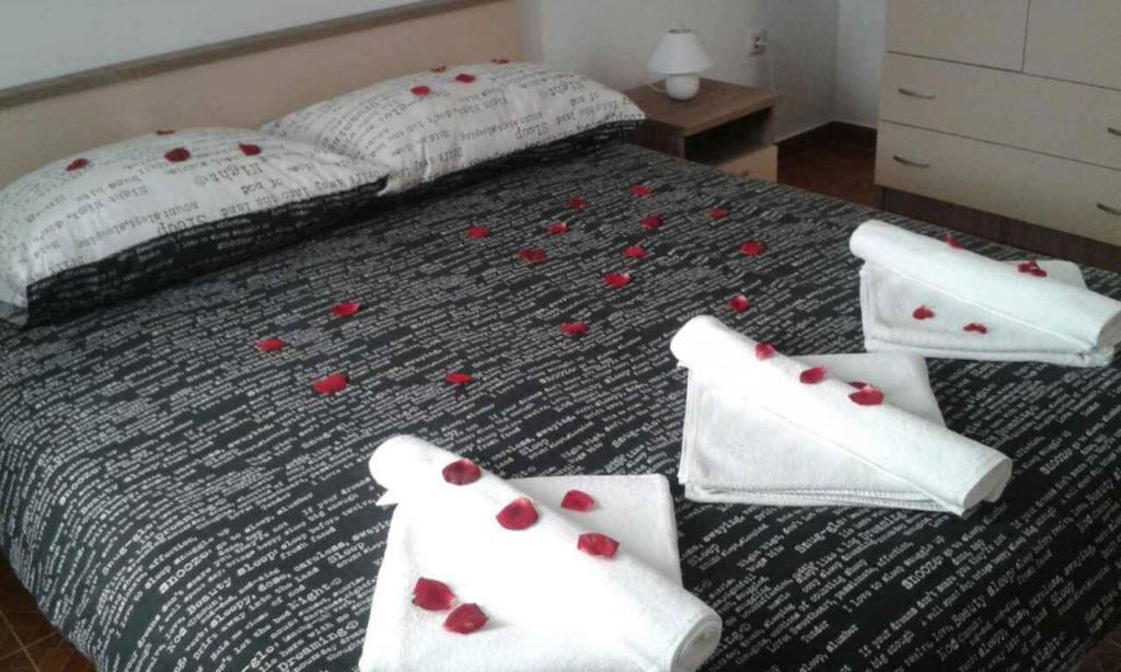 a bed with red rose pedals on the bed at Apartments VRSI 4494 in Vrsi