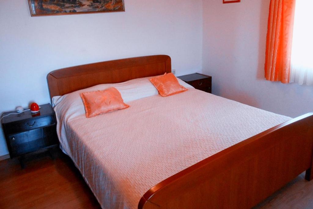 ein Schlafzimmer mit einem Bett mit zwei orangenen Kissen darauf in der Unterkunft Apartments BISERKA (4232) in Poljana